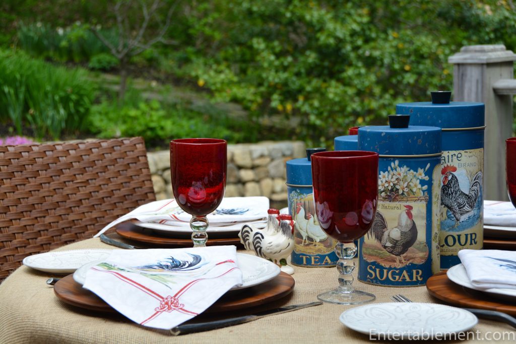 table set with rooster napkins, rooster canisters and blue glasses
